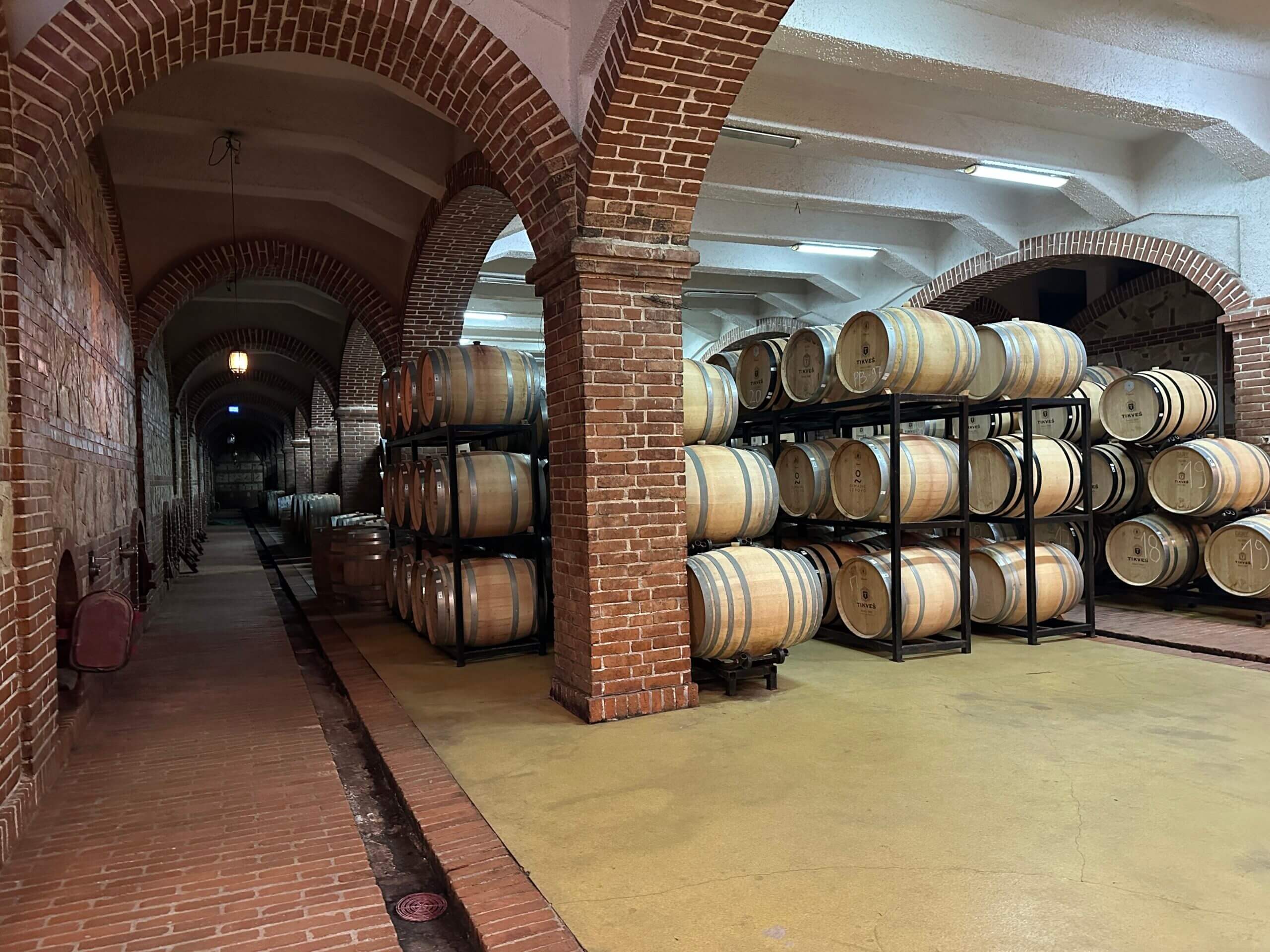 Weinkeller mit Steinwänden und übereinander gelagerten Holzfässern des Tikves-Weingut