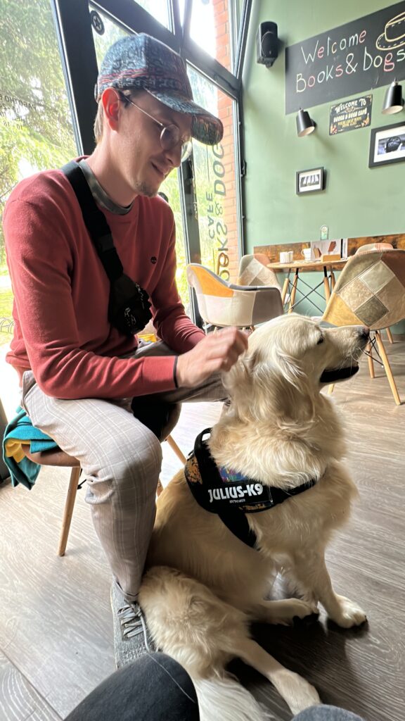 Ein Mann streichelt einen Golden Retriever in einem Café