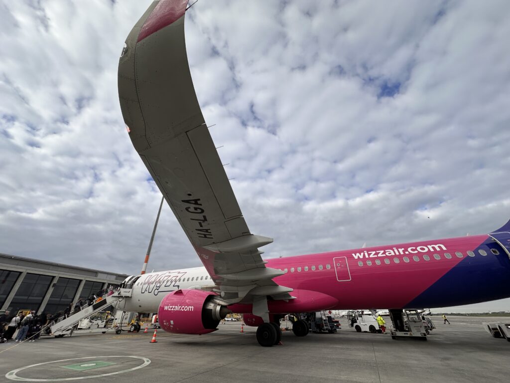 Flugzeug mit auffälligem Heckflügel am Gate unter bewölktem Himmel