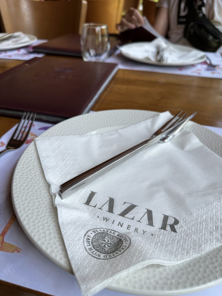 Teller mit Serviette und Besteck von der Lazar Winery in der Tikves-Weinregion mit der Speisekarte im Hintergrund