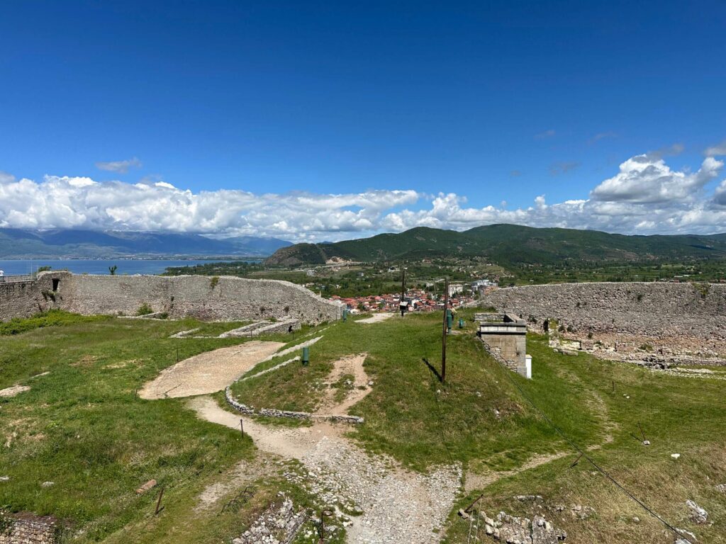 Blick auf die Festung in Ohrid mit grüner Wiese, Steinmauer und Sandwegen