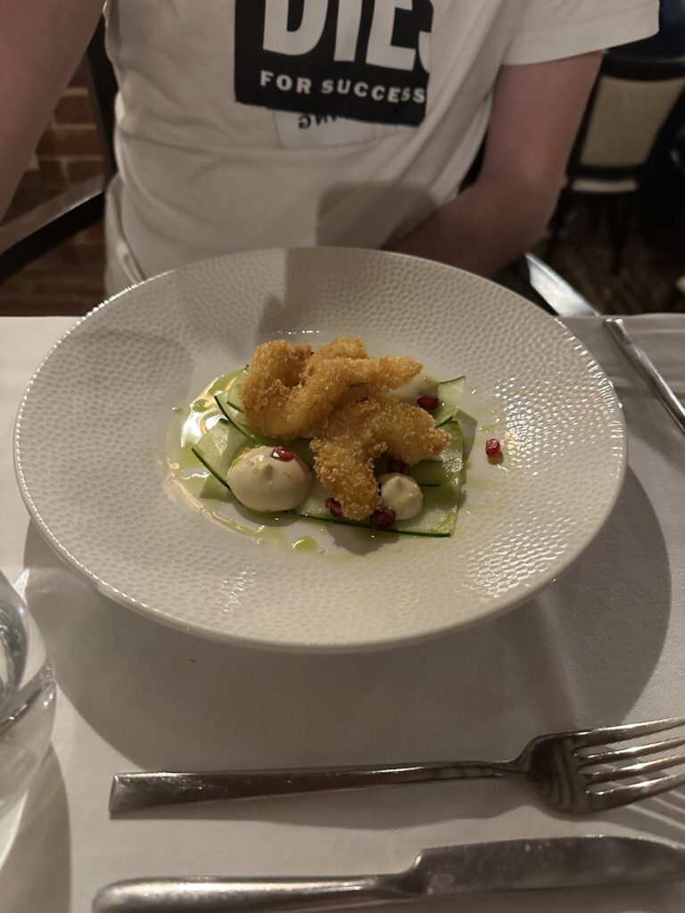 Angerichteter Gang eines Menüs mit gebackenen Schrimps auf Gurkensalat im Restaurant des Tikves-Weingut