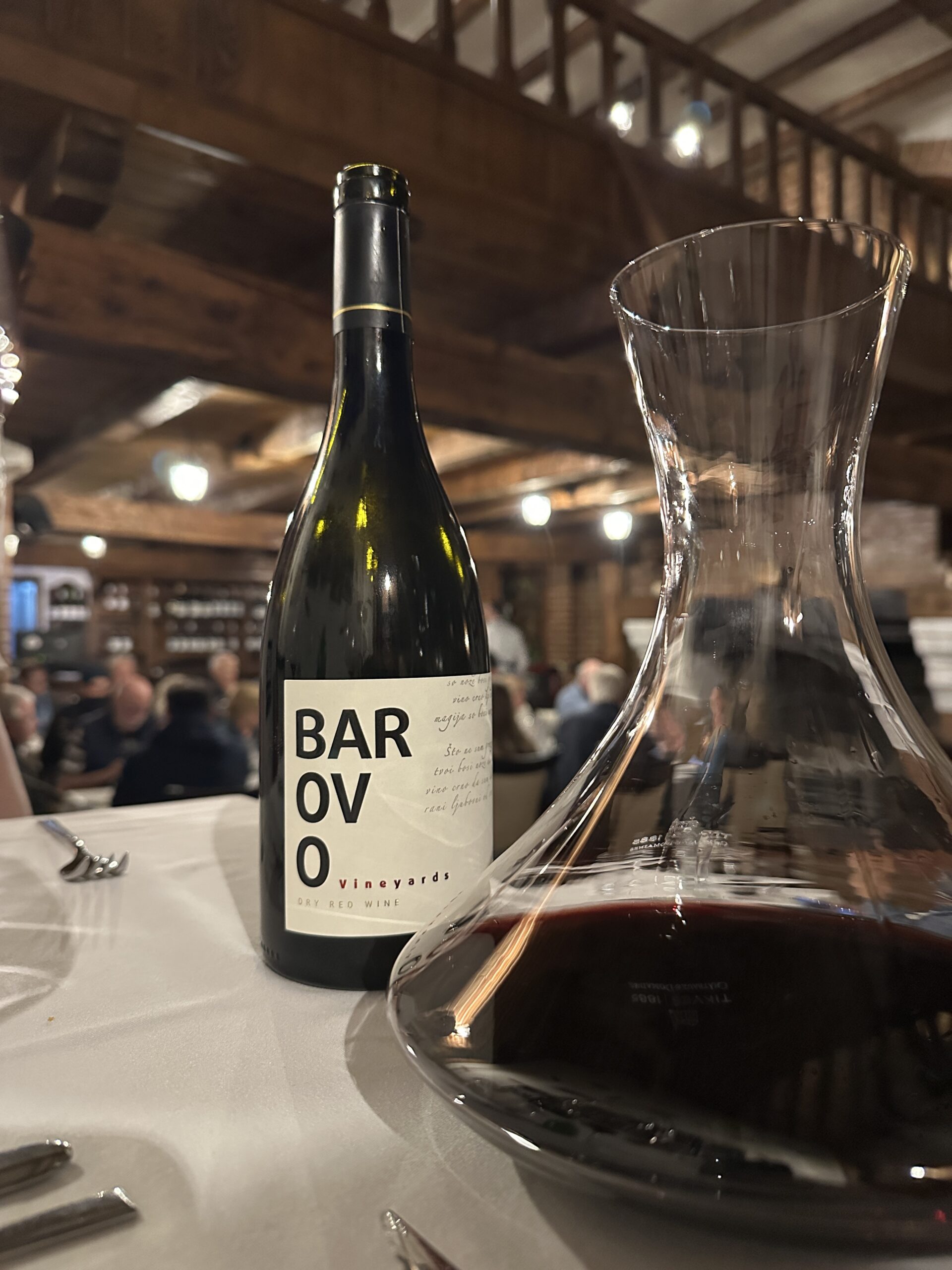 Weinflasche mit halbgefülltem Dekanter auf einem Tisch im Restaurant des Tikves-Weingut