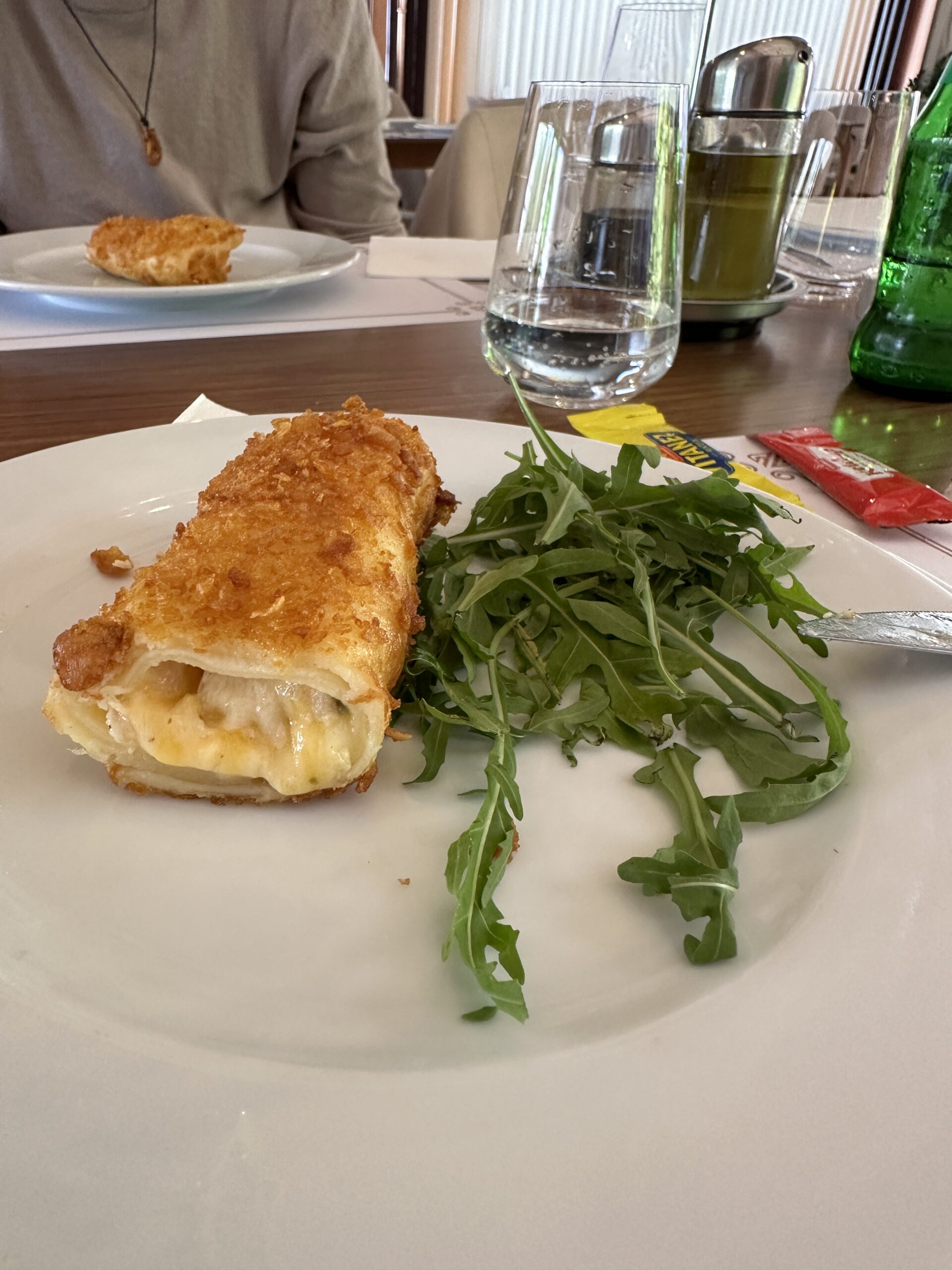 Meat Hand Pie (Piroschki) mit Cheddar, Putenfilet und Gurken auf einem Teller mit Rucola serviert im Restaurant ZEN Gastronomy Concept in Veles