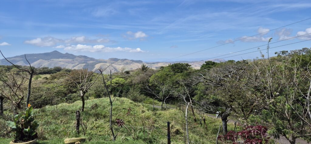 Weite Hügellandschaft mit Bergen im Hintergrund in Costa Rica