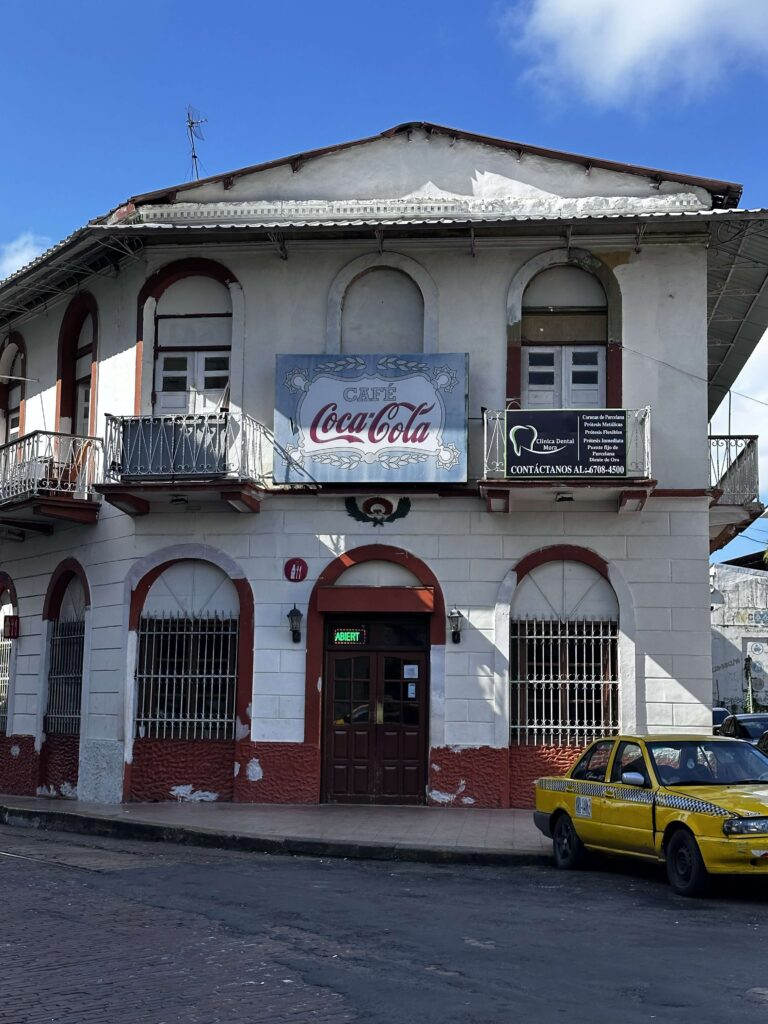 Außenansicht des Coca Cola Cafés mit gelbem Taxi an der Straße im Casco Viejo in Panama-City