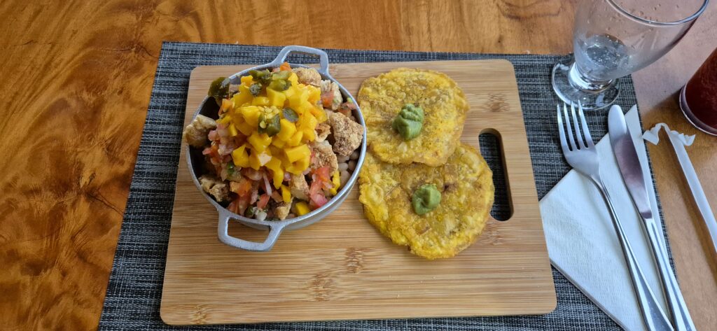 Chifrijo mit Mango-Salsa und Patacones auf Holzbrett serviert